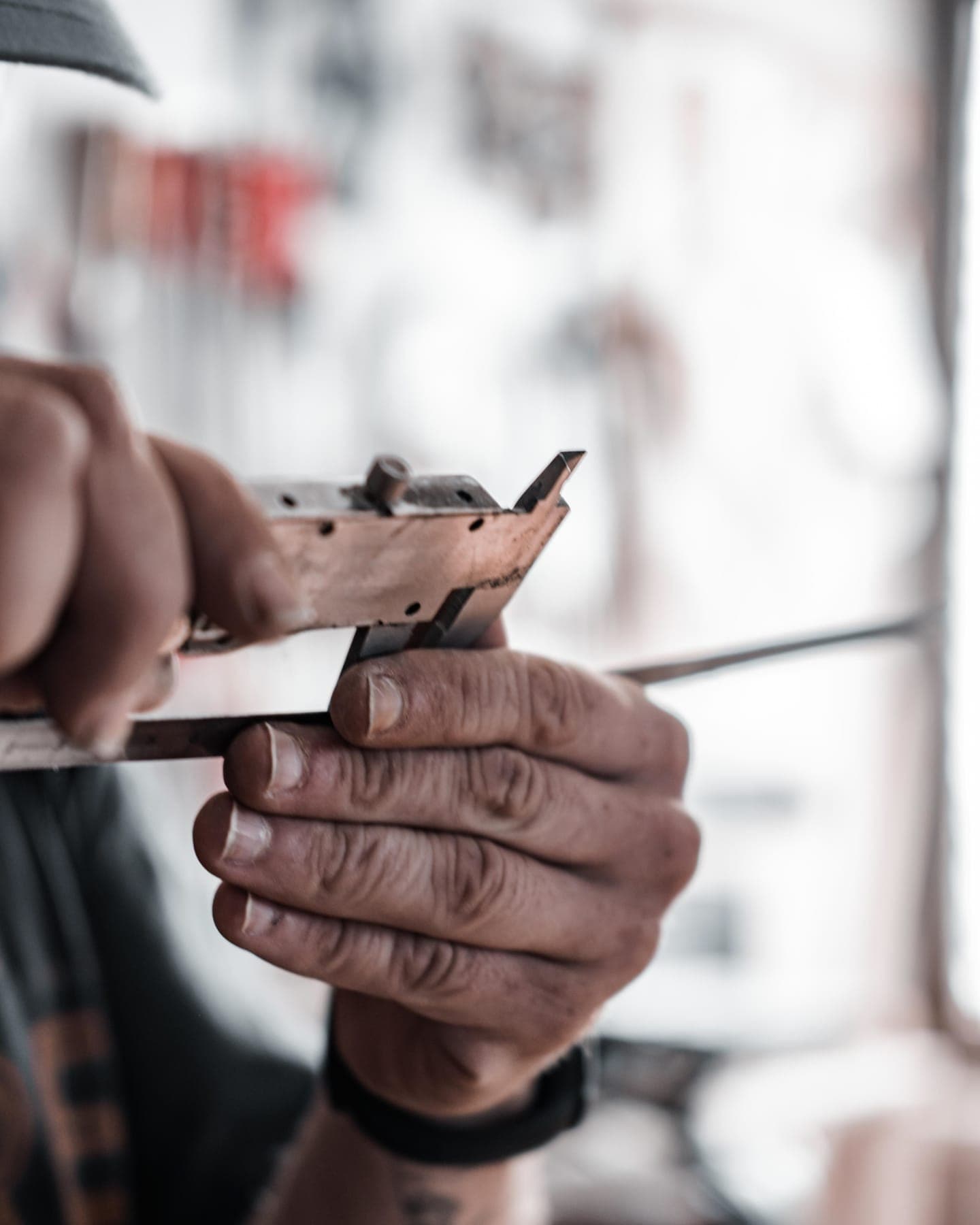 Hands measuring a metal part in a workshop